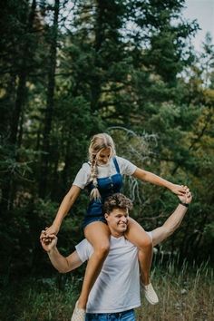 a man carrying a woman on his back in the woods while she holds her up