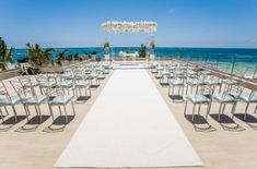 an outdoor ceremony set up with chairs and flowers on the aisle, overlooking the ocean