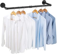 three shirts hanging on a rail and two hangers attached to the rails with clothes in them