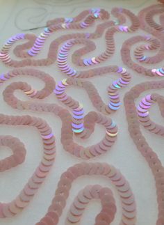 pink and silver spirals are arranged on a white tablecloth with iridescent circles