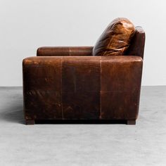 a brown leather chair sitting on top of a cement floor