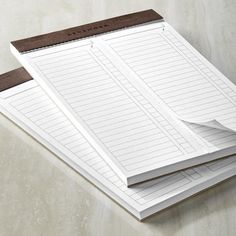 three lined notebooks sitting on top of each other next to a pen and paper pad