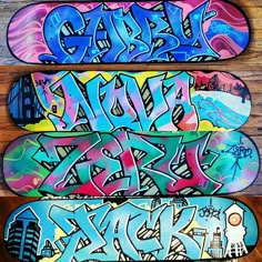 three skateboards covered in graffiti sitting on top of a wooden floor next to each other