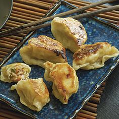 four dumplings on a blue plate with chopsticks