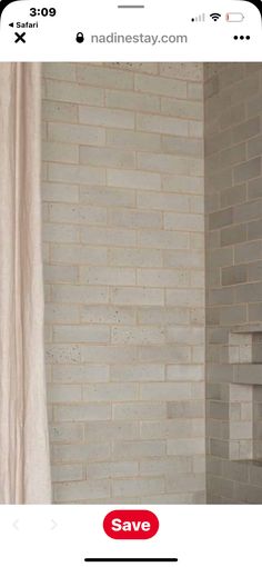 a bathroom with a white brick wall next to a shower