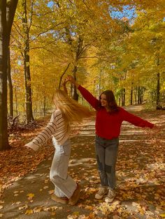 two women are dancing in the fall leaves