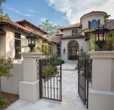 a gated entrance to a house with potted plants on each side and an iron fence