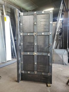 an open metal door with rivets and screws on the sides in a warehouse