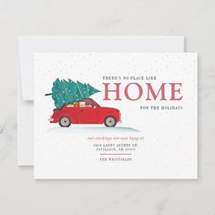 a red car with a christmas tree on the roof is parked in front of a white card