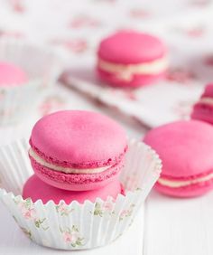 three pink macaroons sitting on top of white paper