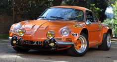 an orange sports car is parked on the side of the road in front of some trees