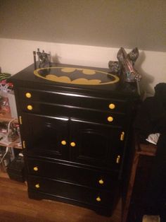 the batman dresser is painted black and has yellow knobs on it's drawers