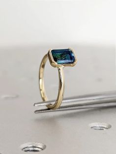 a gold ring with a blue topazte in the center on a silver surface