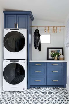 a washer and dryer in a laundry room with blue cabinetry, white counter tops and gold handles