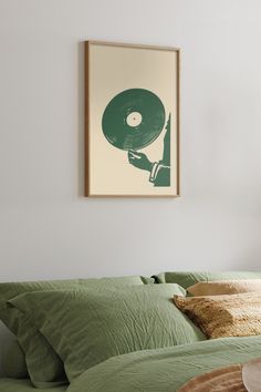 a bed with green sheets, pillows and a framed record player on the wall above it