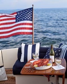 a plate of lobsters on a wooden table next to the ocean and an american flag