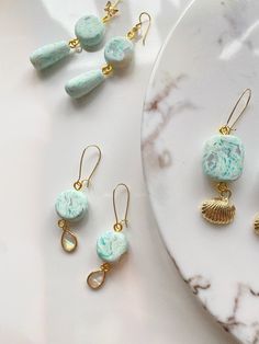 three pieces of jewelry sitting on top of a white plate next to some gold earrings