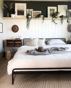 a white bed sitting in a bedroom next to a wall with pictures hanging on it