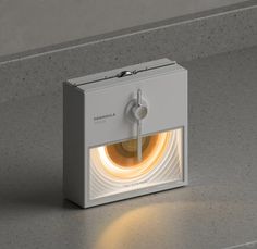 a white box with a yellow light in it on a countertop next to a gray wall