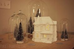 three snow globes sitting on top of a table next to a house and trees