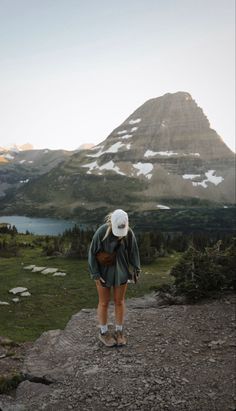 a woman standing on top of a mountain looking at the mountains and lake below her