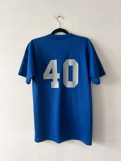 a blue shirt with the number 40 on it hanging from a hanger against a white wall