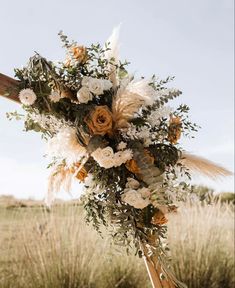 a bouquet of flowers on top of a wooden pole in the middle of a field