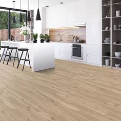 an open kitchen with white cabinets and wood flooring, along with bar stools