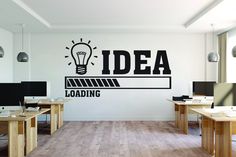 an office with desks and computer screens on the wall that says idea loading in black