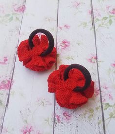 two crocheted red and black hair clips on top of a flowered table