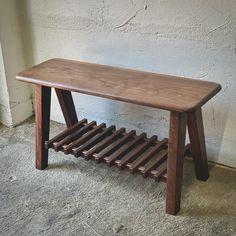 a wooden bench sitting in front of a white wall with a shelf on it's side