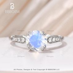 a white gold ring with an oval blue stone surrounded by diamonds