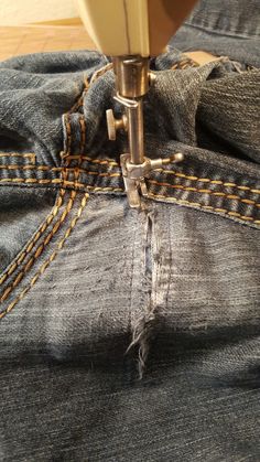 the sewing machine is stitching through jeans