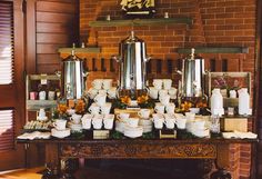 a table with many cups and saucers sitting on it's side in front of a brick wall