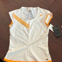 A Climacool Tennis Top. Cute It’s White With Light Orange Trim And Stripes. There’s Also A Sheer Lines That Come To A V Tennis Uniforms, Tennis Top, Adidas Orange, Tennis Tops, Tennis Shop, Tennis Fashion, Top Cute, Adidas Tops, Light Orange