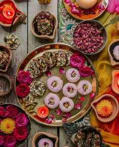 the table is covered with many different types of flowers and donuts in bowls on it