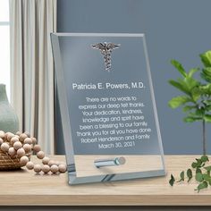 an acrylic plaque with a medical symbol on it next to some beads and a potted plant