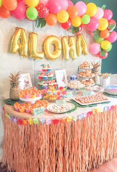 an aloha themed party with balloons and tassels on the table for dessert