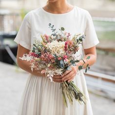 a woman holding a bouquet of flowers in her hands