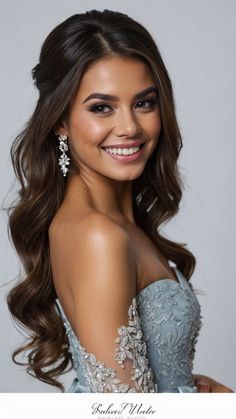 a beautiful young woman in a blue dress smiling at the camera with her hair pulled back