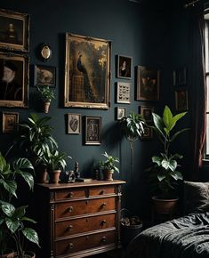 a bedroom with dark green walls and lots of plants on the dresser next to it