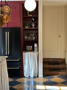 a kitchen with black and white checkered flooring next to a red bookcase