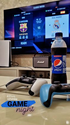 a bottle of pepsi soda sitting on top of a table next to video game controllers