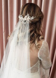 the back of a bride's head wearing a veil with flowers on it and hair comb