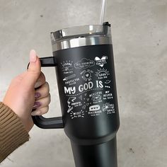 a person holding a black coffee cup with writing on the bottom and inside, in front of a white background