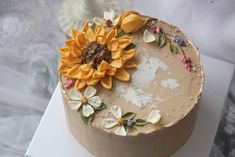 a cake decorated with sunflowers on top of a white tablecloth covered surface