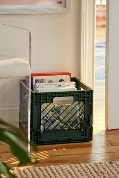 a green crate sitting on top of a hard wood floor next to a white door