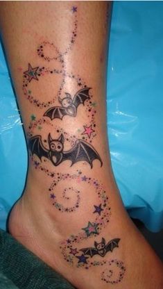 a tattoo on the leg of a woman with bats and stars all over her body