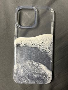 a phone case with an image of the ocean on it, sitting on a bed