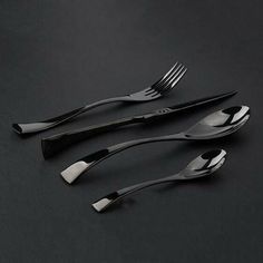 three forks and two spoons on a black surface with one fork in the middle